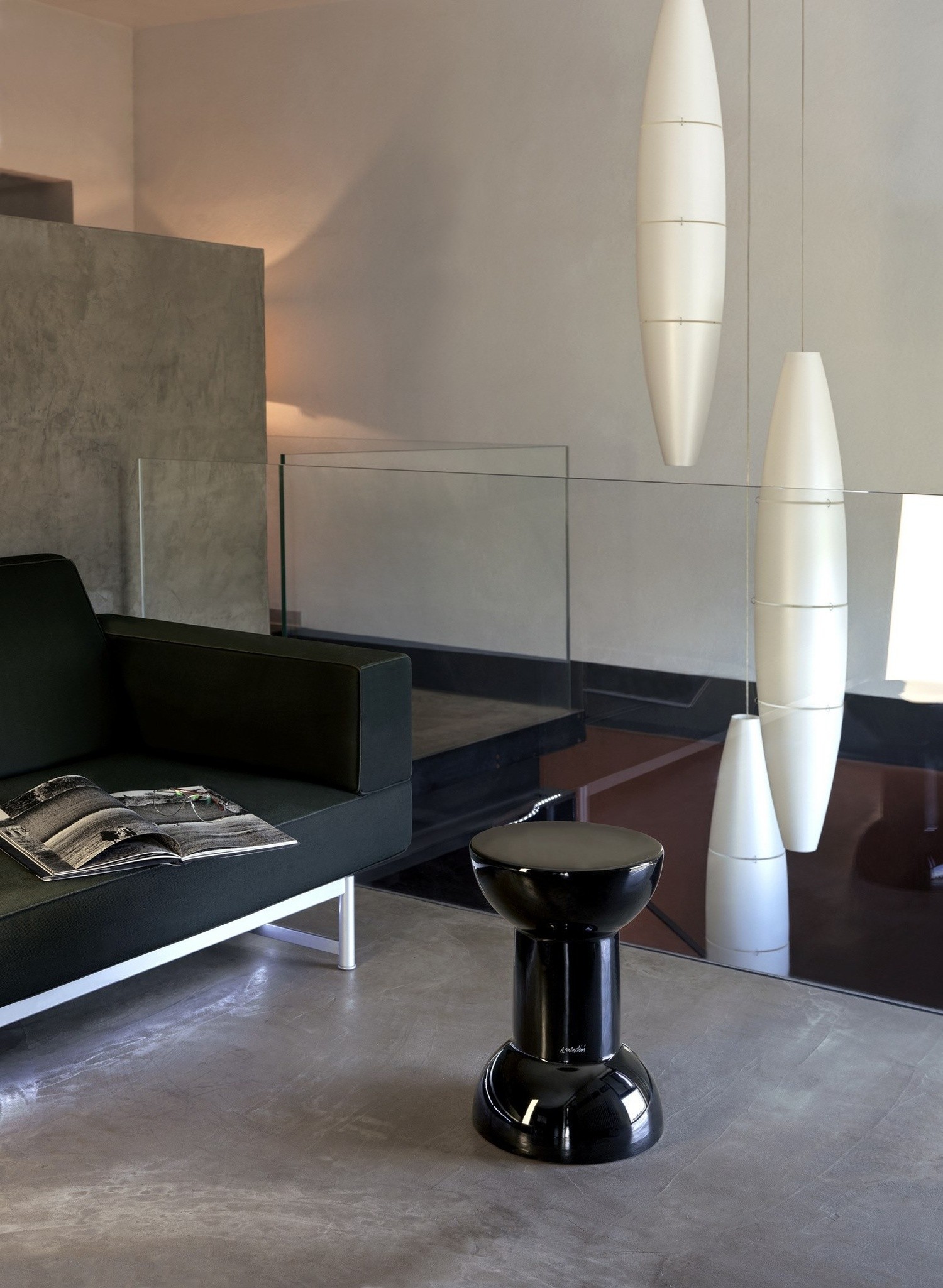 Minimalistyczny salon z czarnym stołkiem i lampą, fot. Flaminia