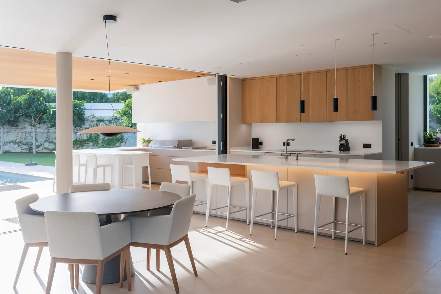 Jasna minimalistyczna kuchnia z wyspą i jadalnią. fot. Porcelanosa