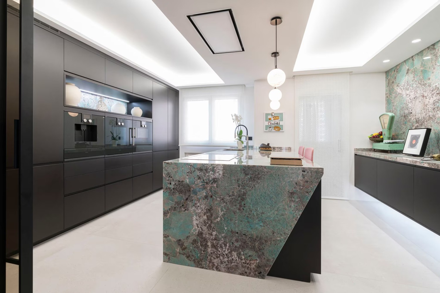 Minimalistyczna kuchnia z kamienną wyspą i zieloną ścianą. fot. Porcelanosa