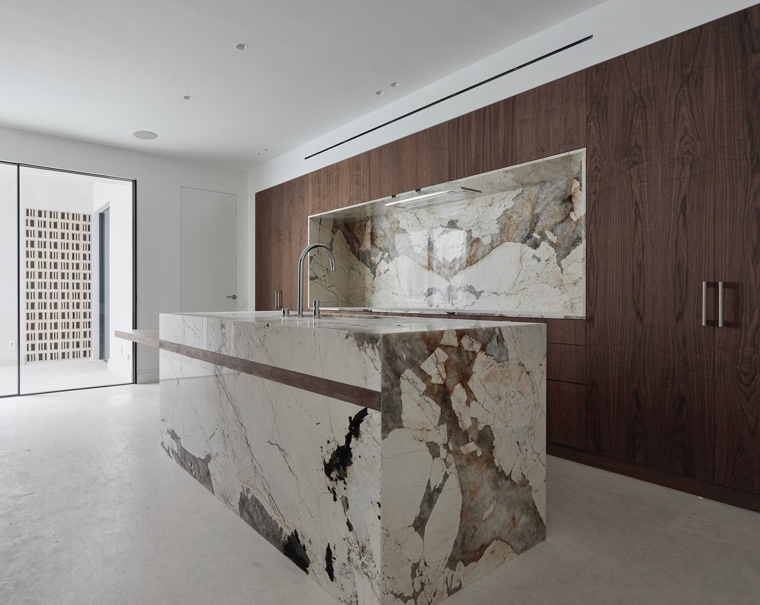 Minimalistyczna kuchnia z marmurową wyspą i drewnem. fot. Porcelanosa