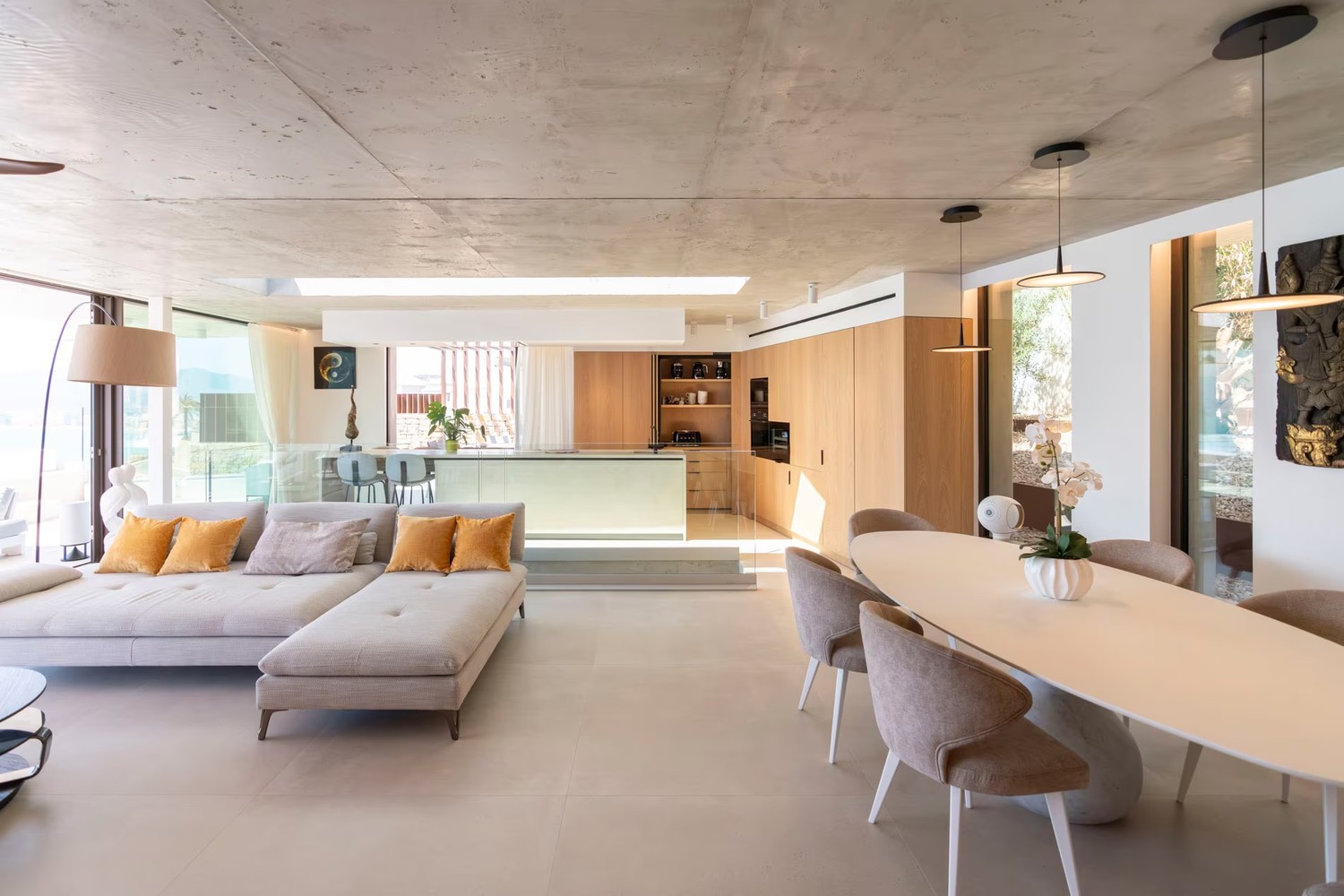 Minimalistyczny salon z jadalnią i drewnianą kuchnią. fot. Porcelanosa