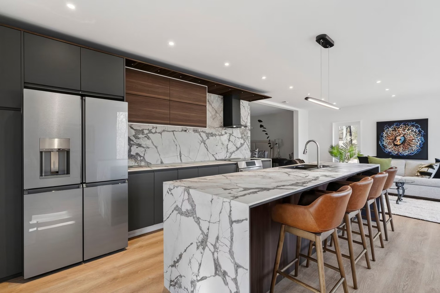 Minimalistyczna kuchnia z marmurową wyspą i salonem. fot. Porcelanosa