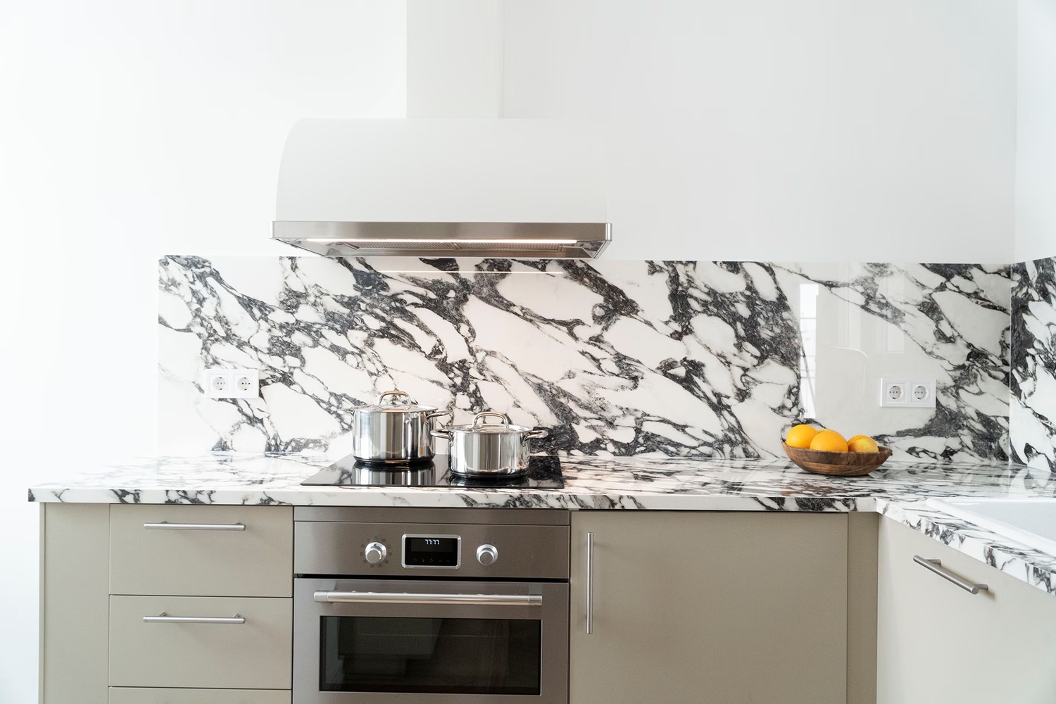 Minimalistyczna kuchnia z marmurowym blatem i okapem. fot. Porcelanosa