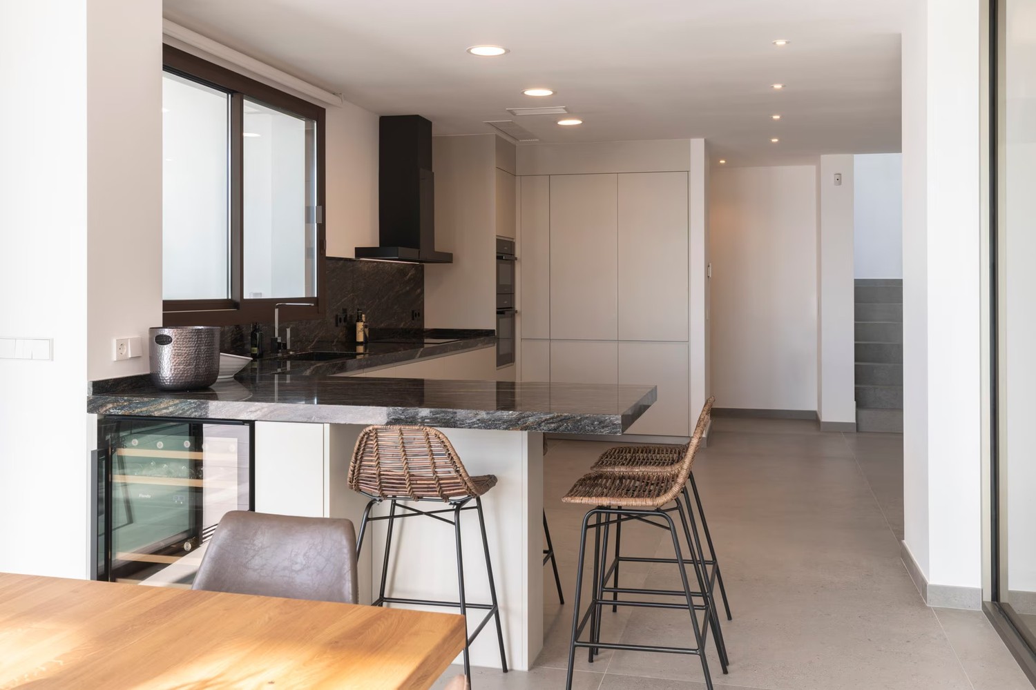 Minimalistyczna kuchnia z kamienną wyspą i oknem. fot. Porcelanosa