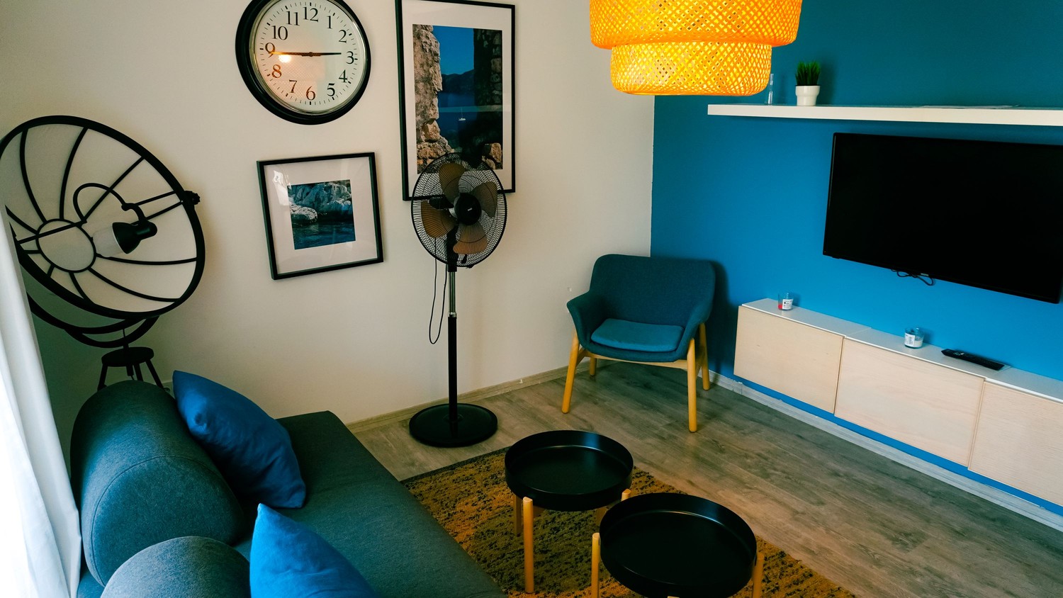 Nowoczesny salon z niebieskim fotelem i obrazami fot. Pexels