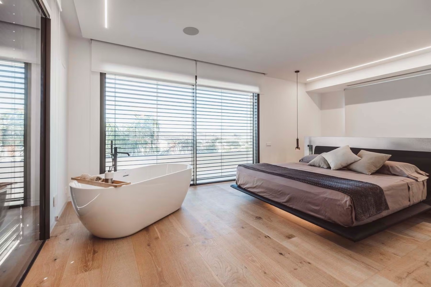 Minimalistyczna sypialnia z białą wanną przy oknie fot. Porcelanosa