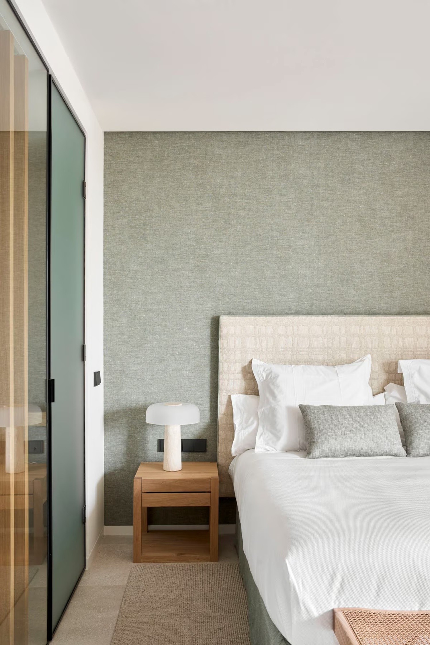 Minimalistyczna sypialnia z tapicerowanym łóżkiem i drewnem. fot. Porcelanosa