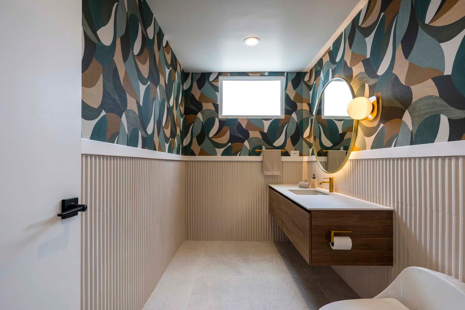 Eklektyczna łazienka z tapetą i złotą armaturą. fot. Porcelanosa