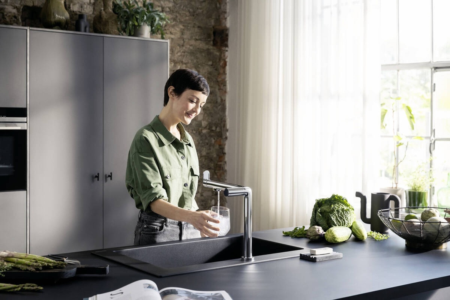 Kobieta przy czarnym zlewie w industrialnej kuchni fot. Hansgrohe